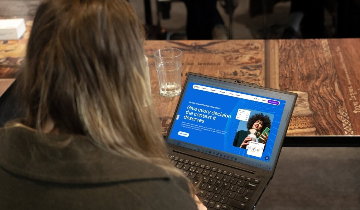 a girl watching a laptop screen with a Qualtrics homepage on it