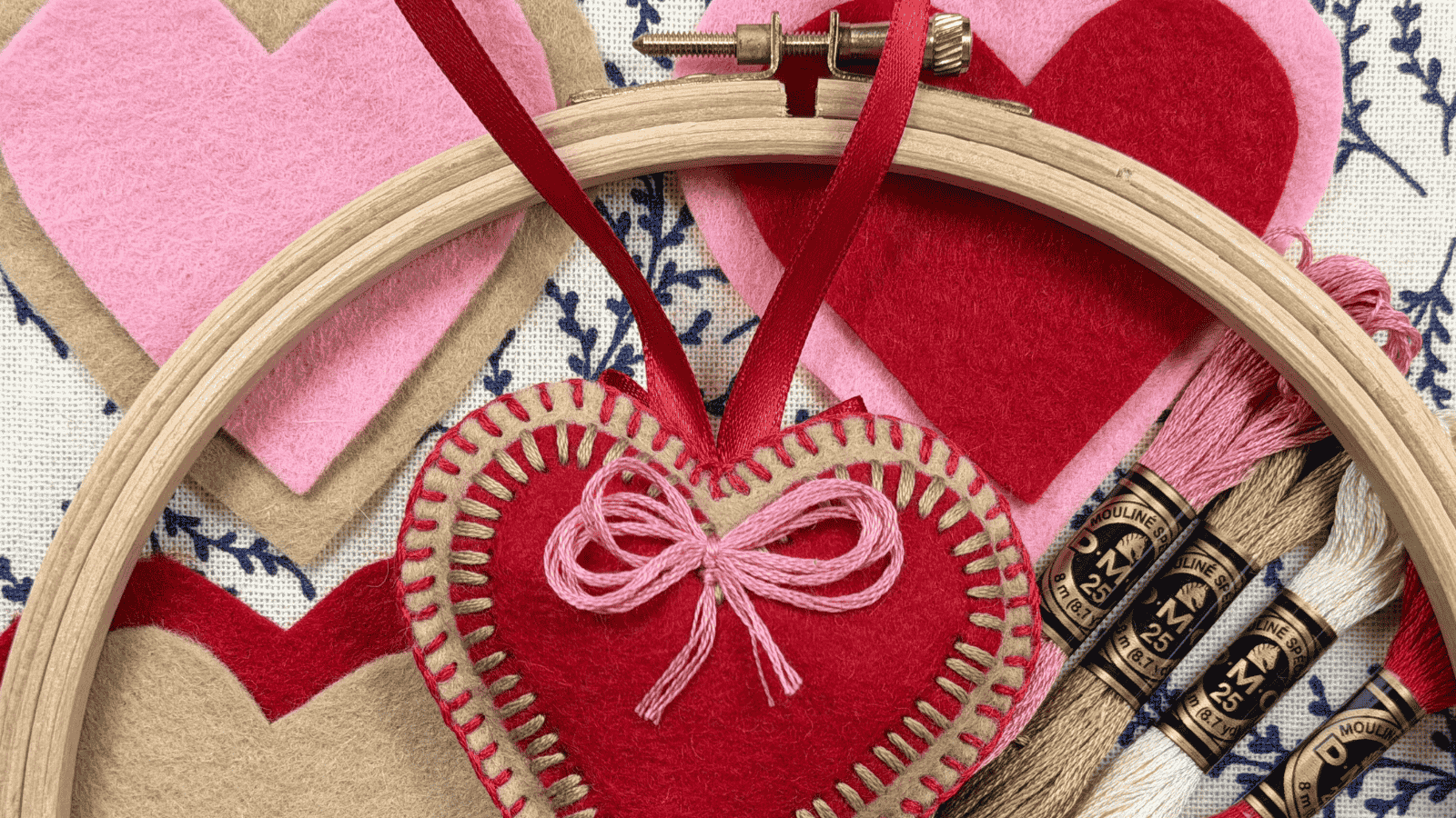 Heart-shaped felt ornaments and embroidery hoops with Valentine's Day craft supplies.