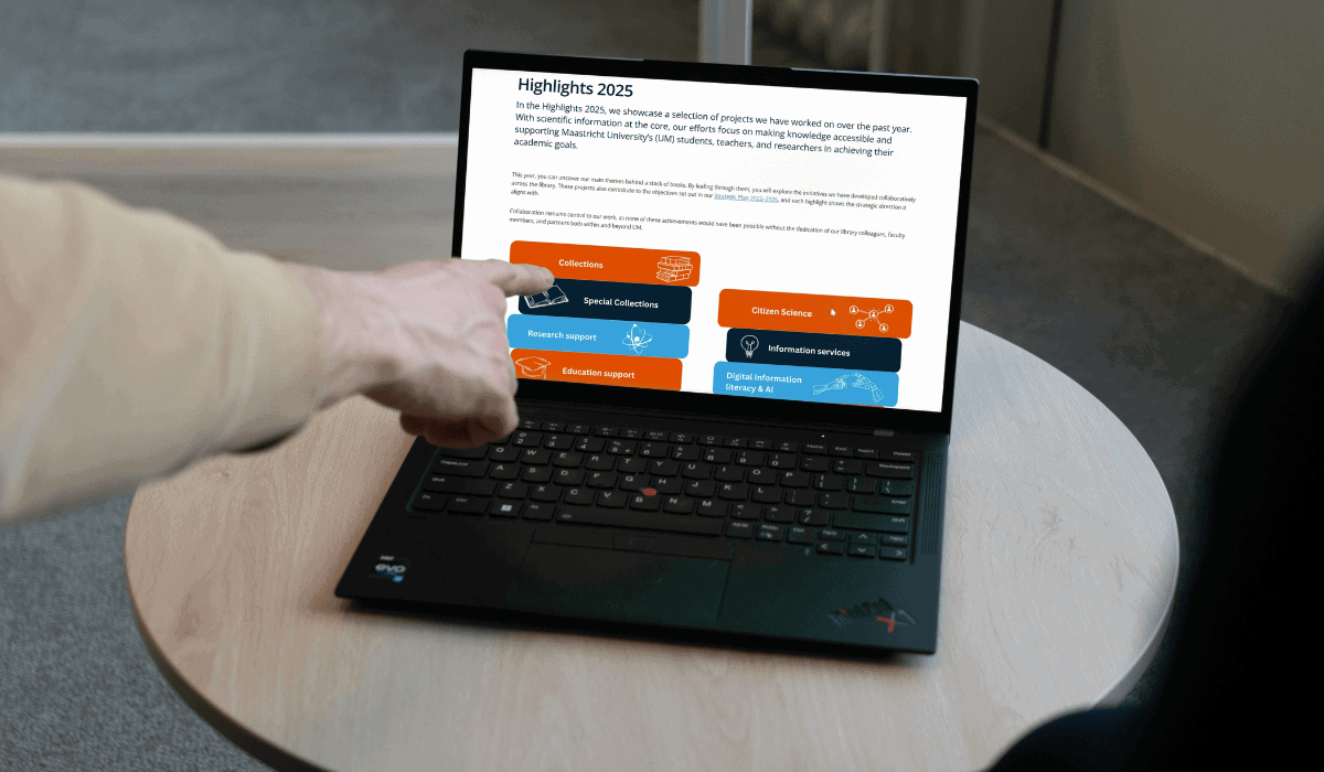 Person pointing at research highlights on a laptop screen at Maastricht University Library.