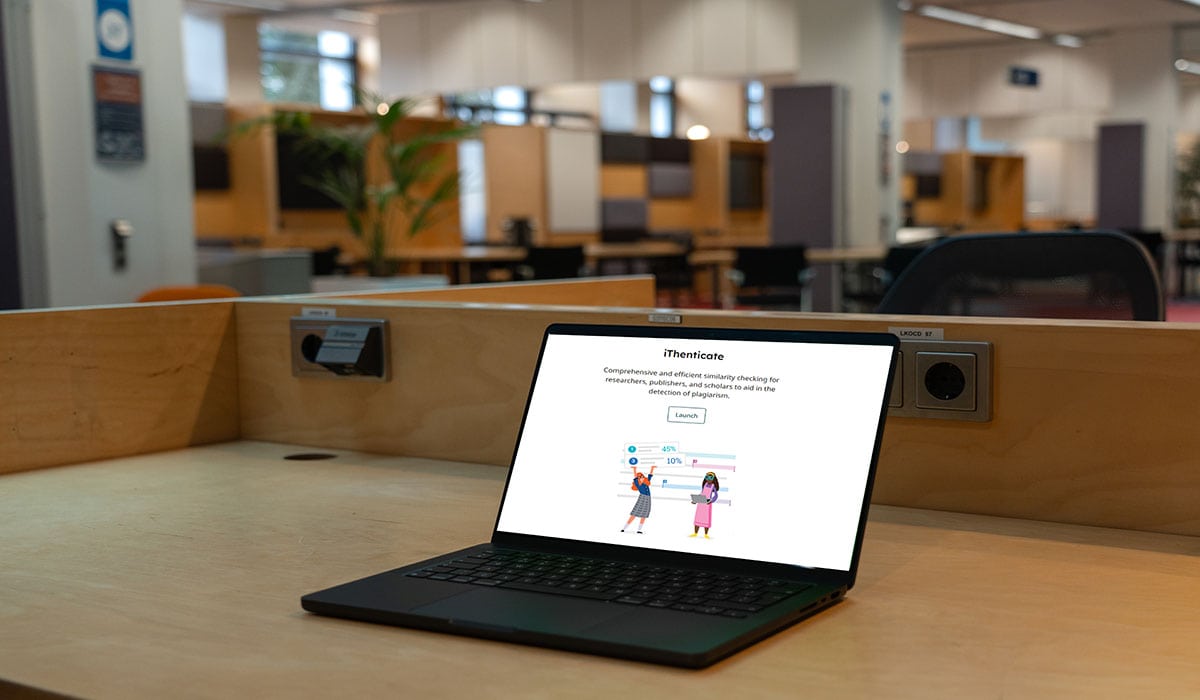 Laptop displaying iThenticate 2.0 interface in library setting.