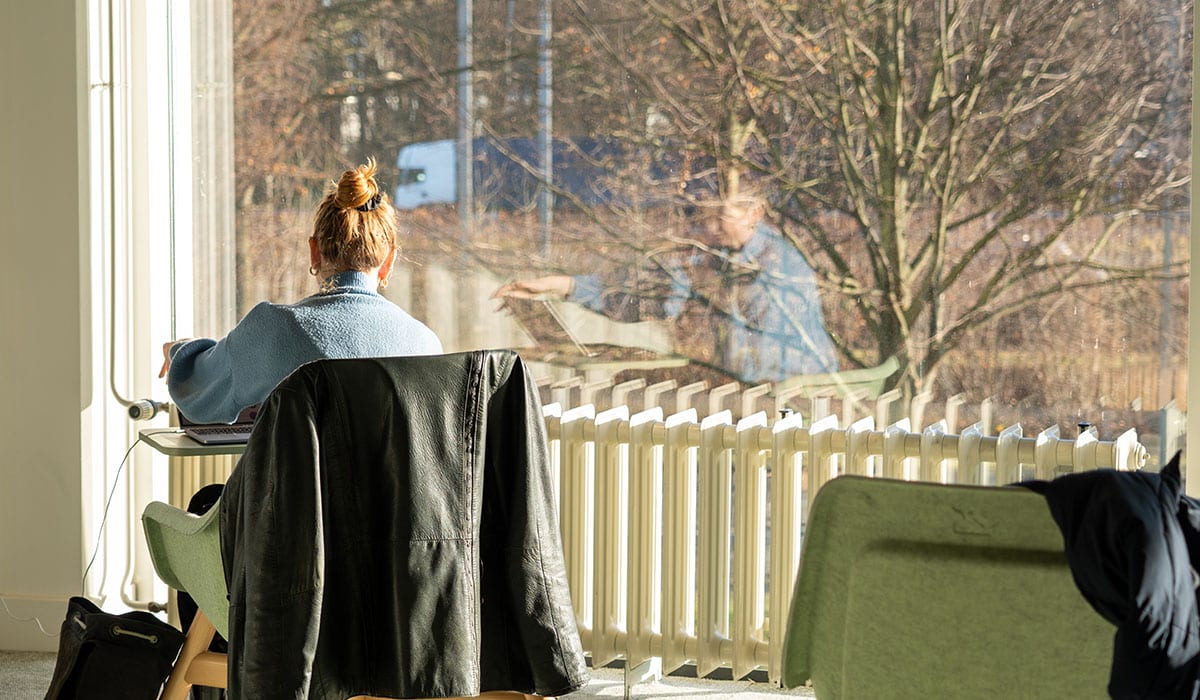Student studying at Maastricht University Library with large window view.