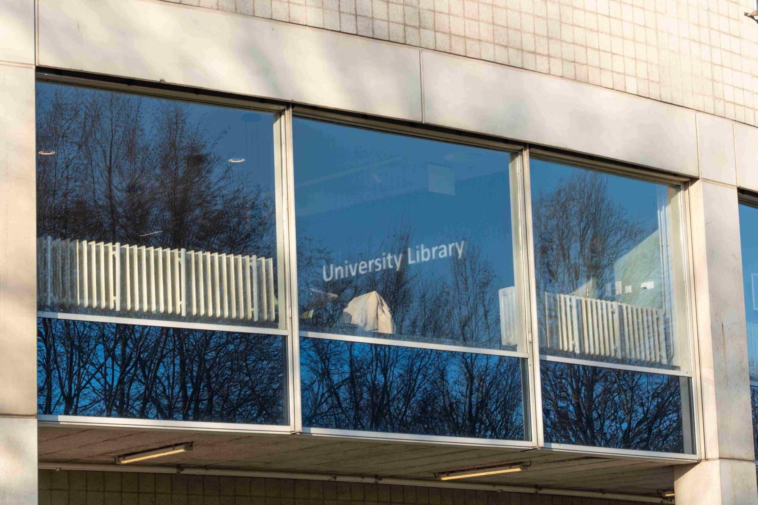 picture of a building and through the window a sign of University Library is seen