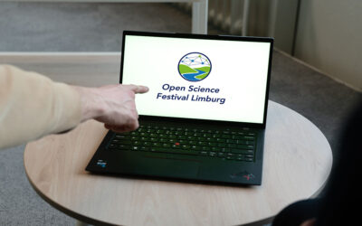 A person points at a laptop showing the Open Science Festival Limburg logo, promoting the upcoming event.