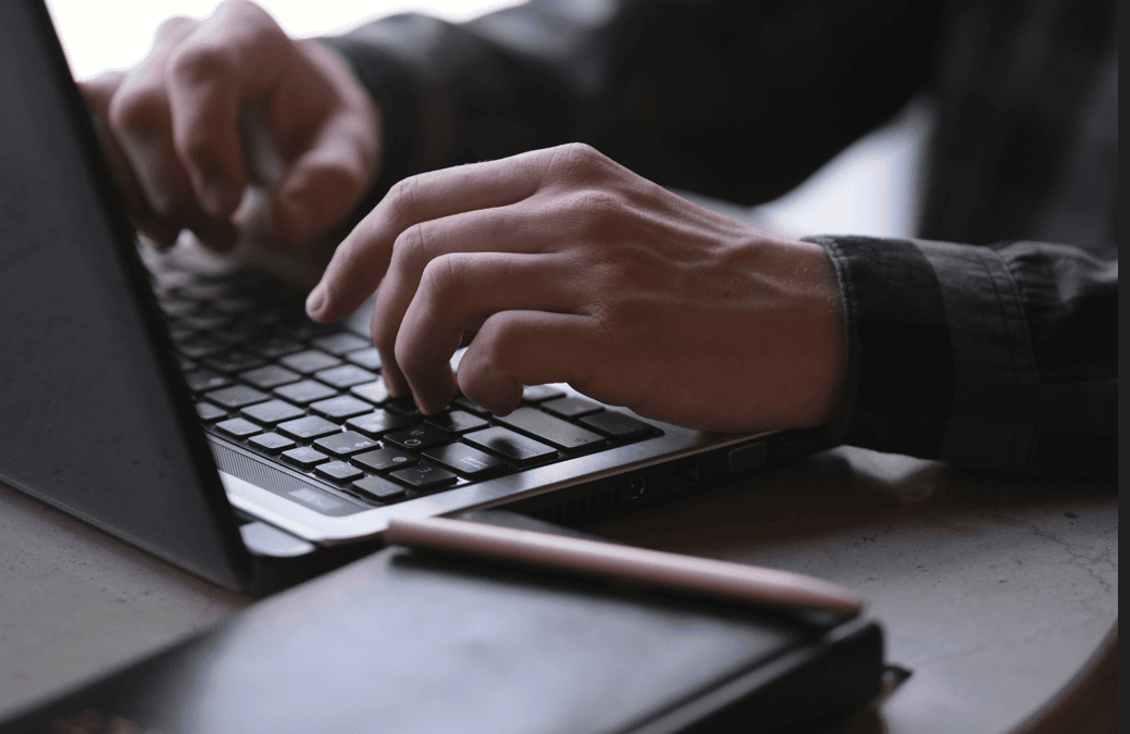 Hands typing on a laptop keyboard during work or study.