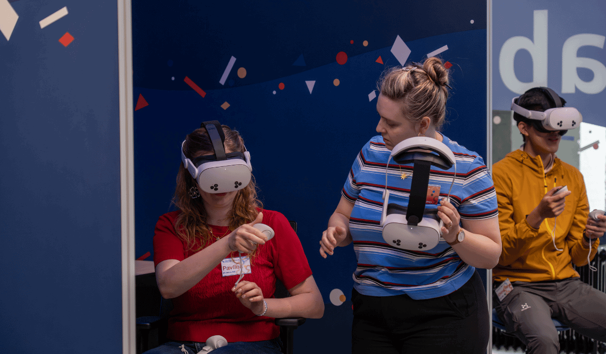 A photo of a person using VR glasses with an instructor next to her.