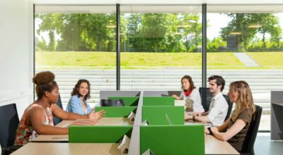 5 students are sitting on their own table while looking at each other and having a conversation
