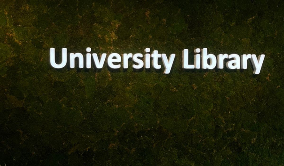 a green wall with University Library in neon letters