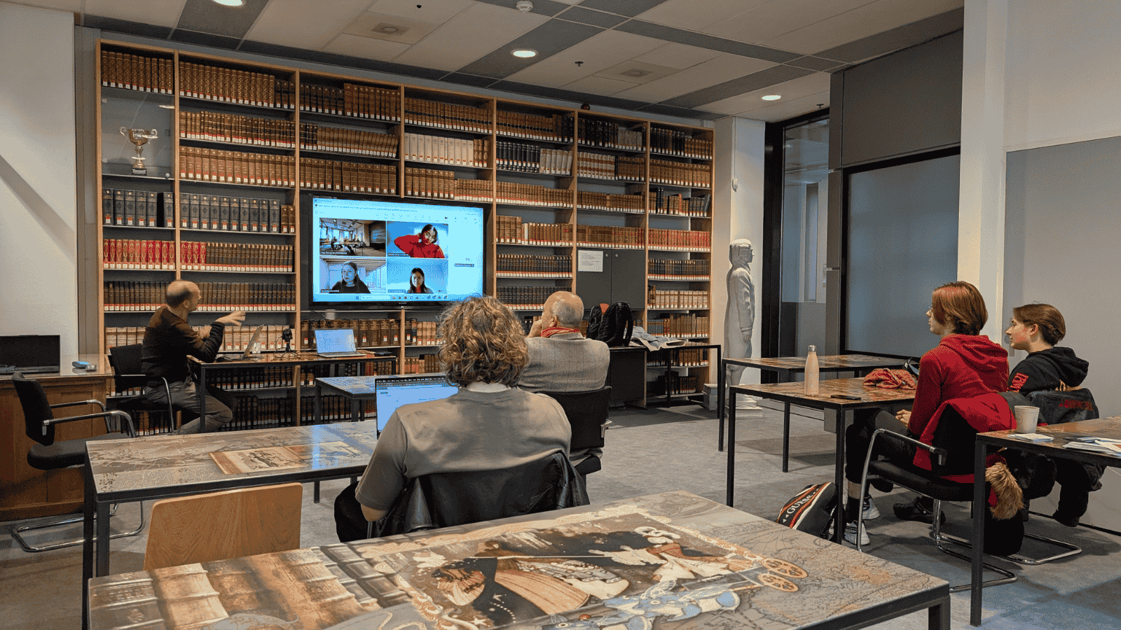 Online study session at Maastricht University Library with students and a digital instructor display.
