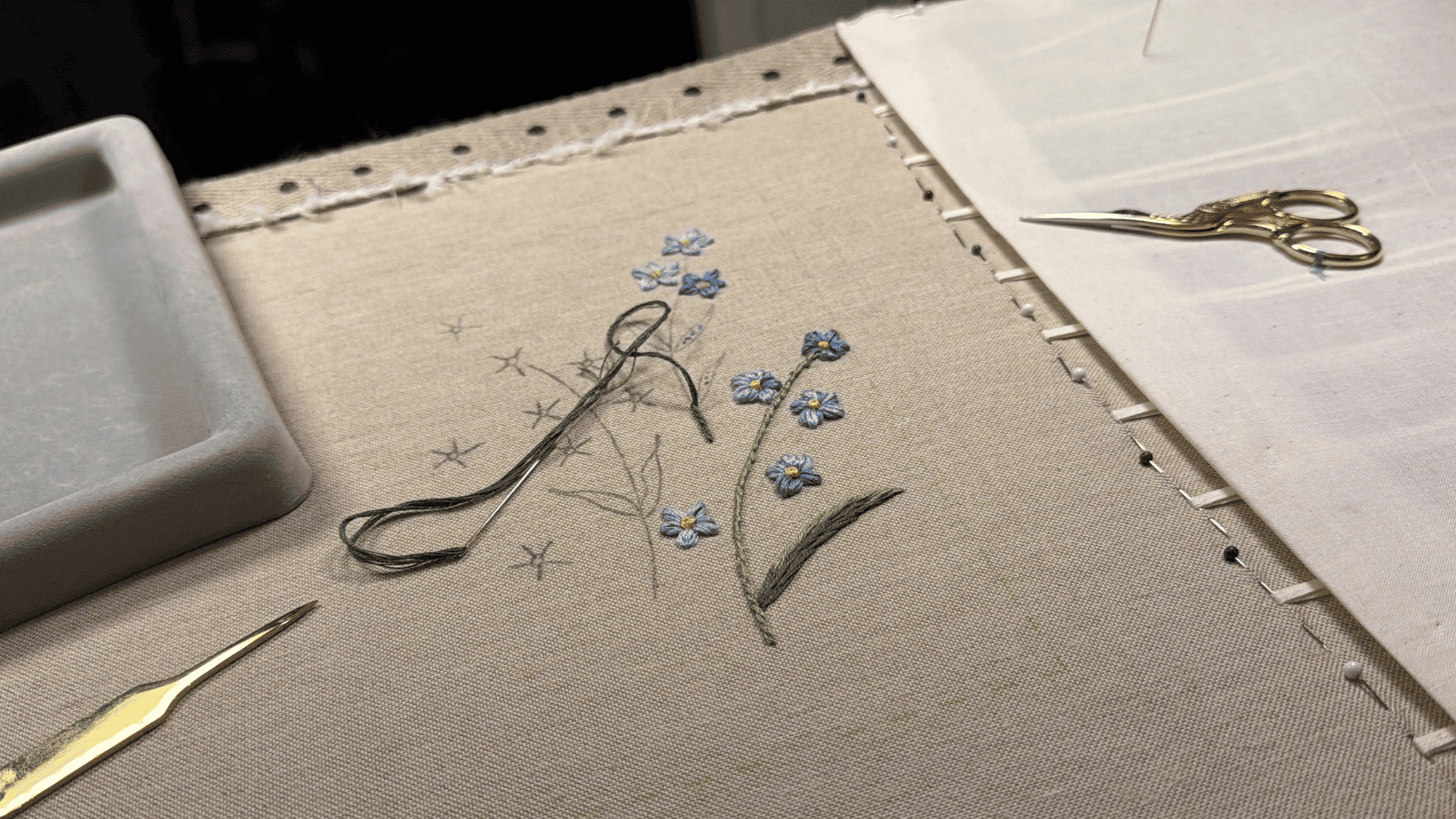 Delicate embroidery of blue flowers on beige fabric at Maastricht University Library.