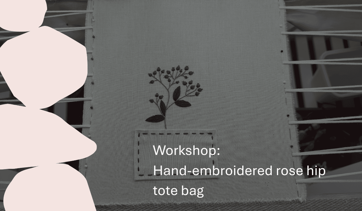 A woman demonstrating a hand-embroidered rose hip tote bag at a workshop.