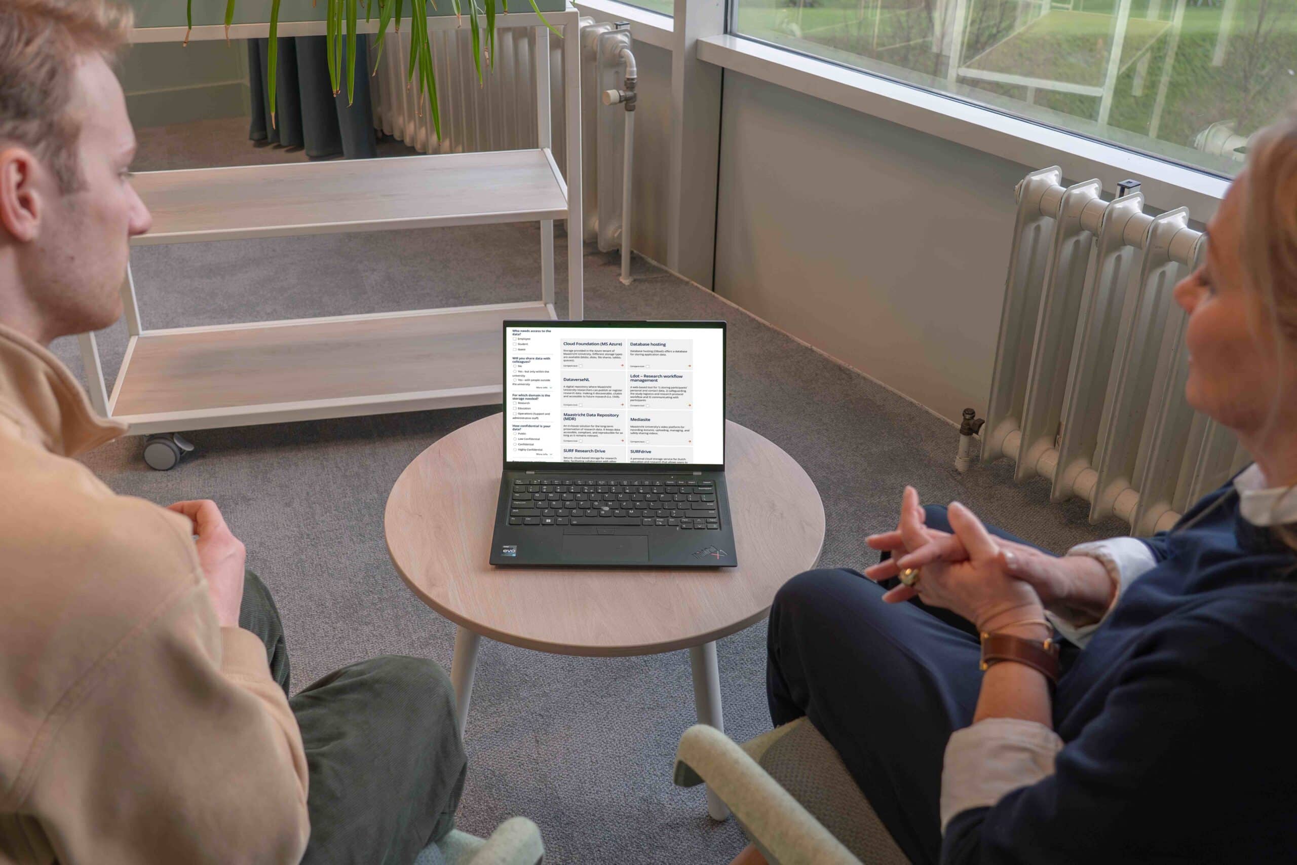 Two people having a discussion with a laptop showing the storage finder.