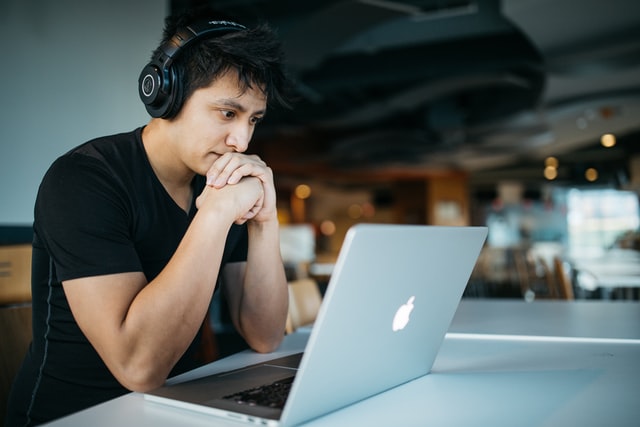 guy with headphones studying on a macbook